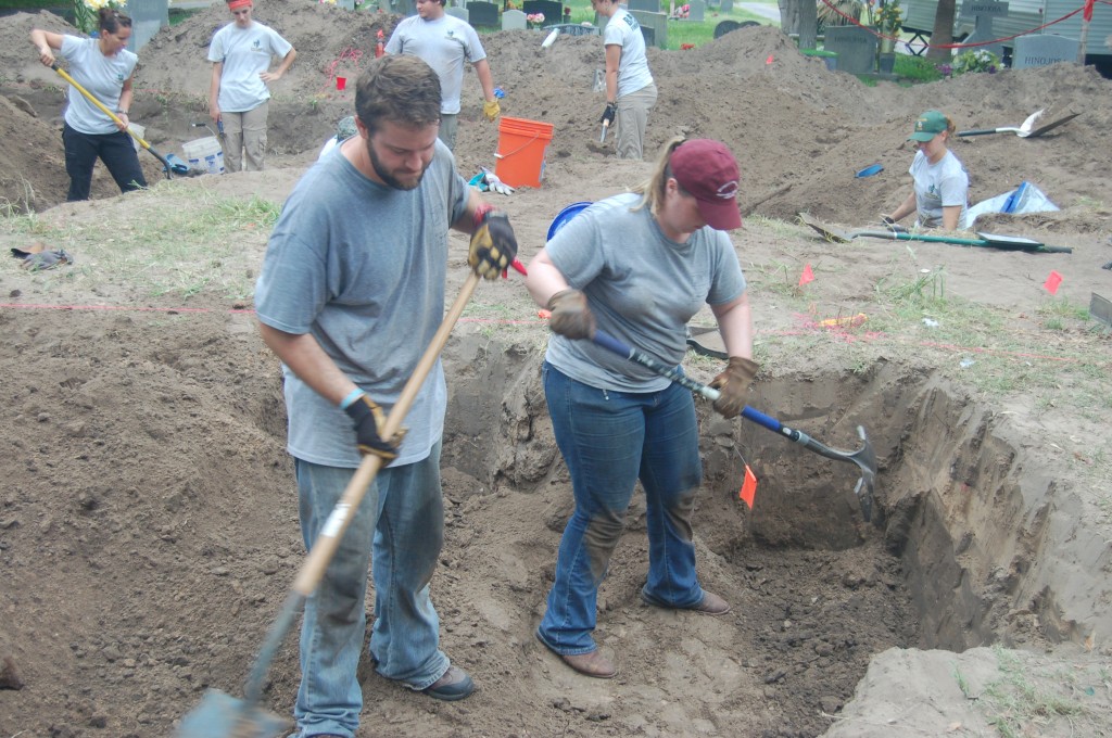 Team members digging in a burial with shovels 