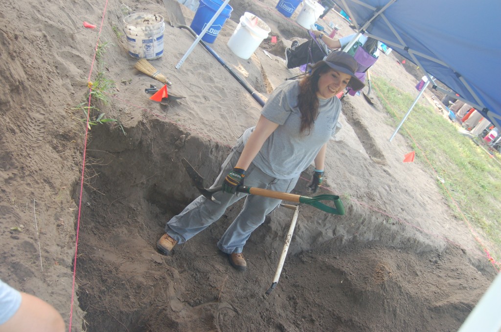 Erica standing in a burial with a shovel