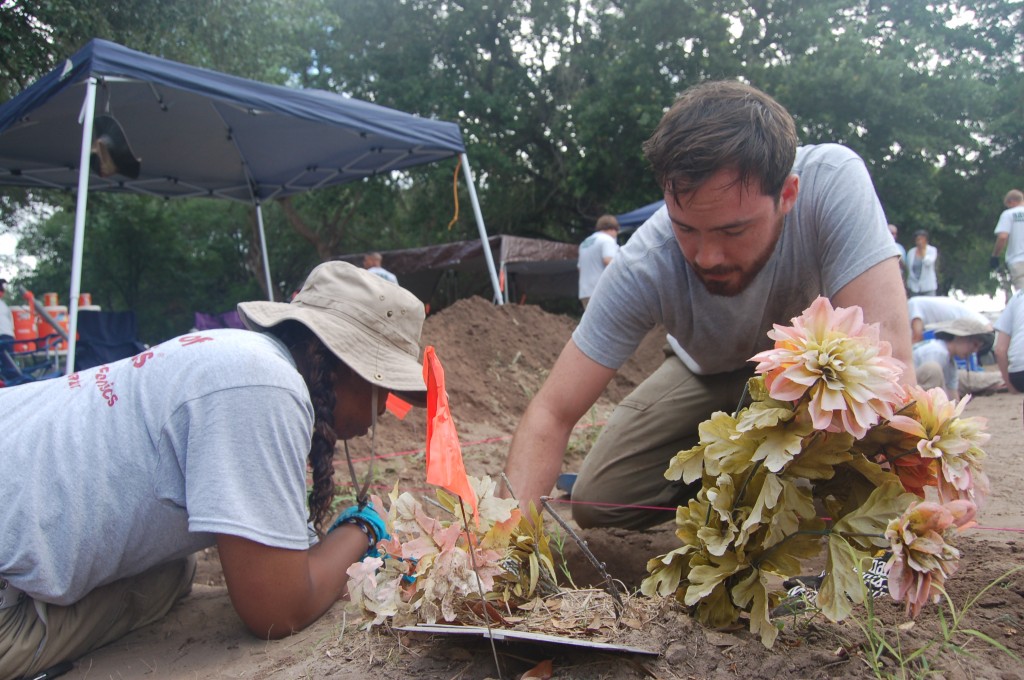 Team members working around a burial marker from the ground surface
