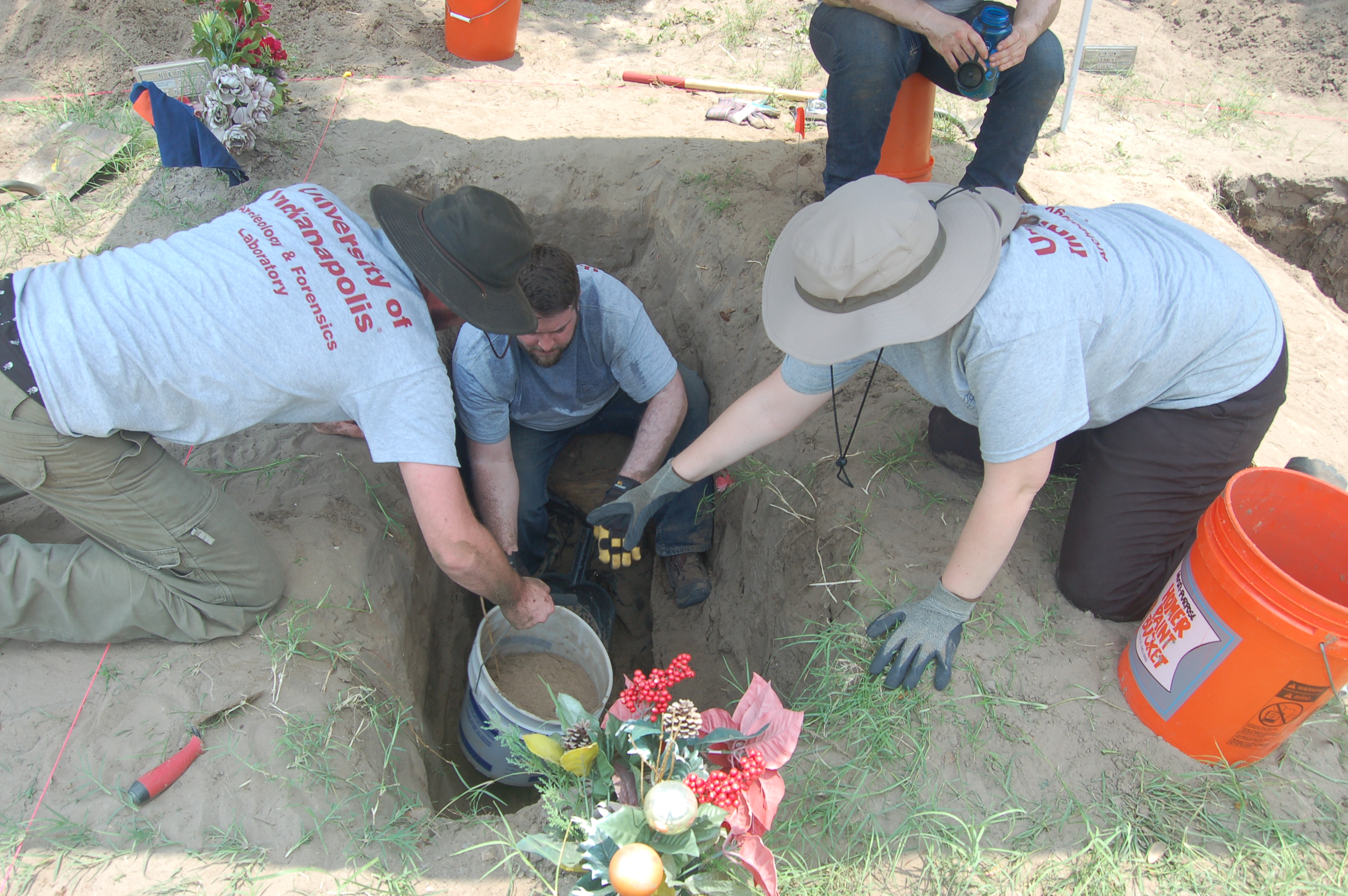 Beyond borders team members taking a bucket of dirt from a team member in a burial