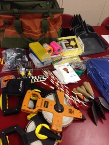Field gear like measuring tapes, trowels, pins, north arrow, strings, and more all laid out before being put in the field bag