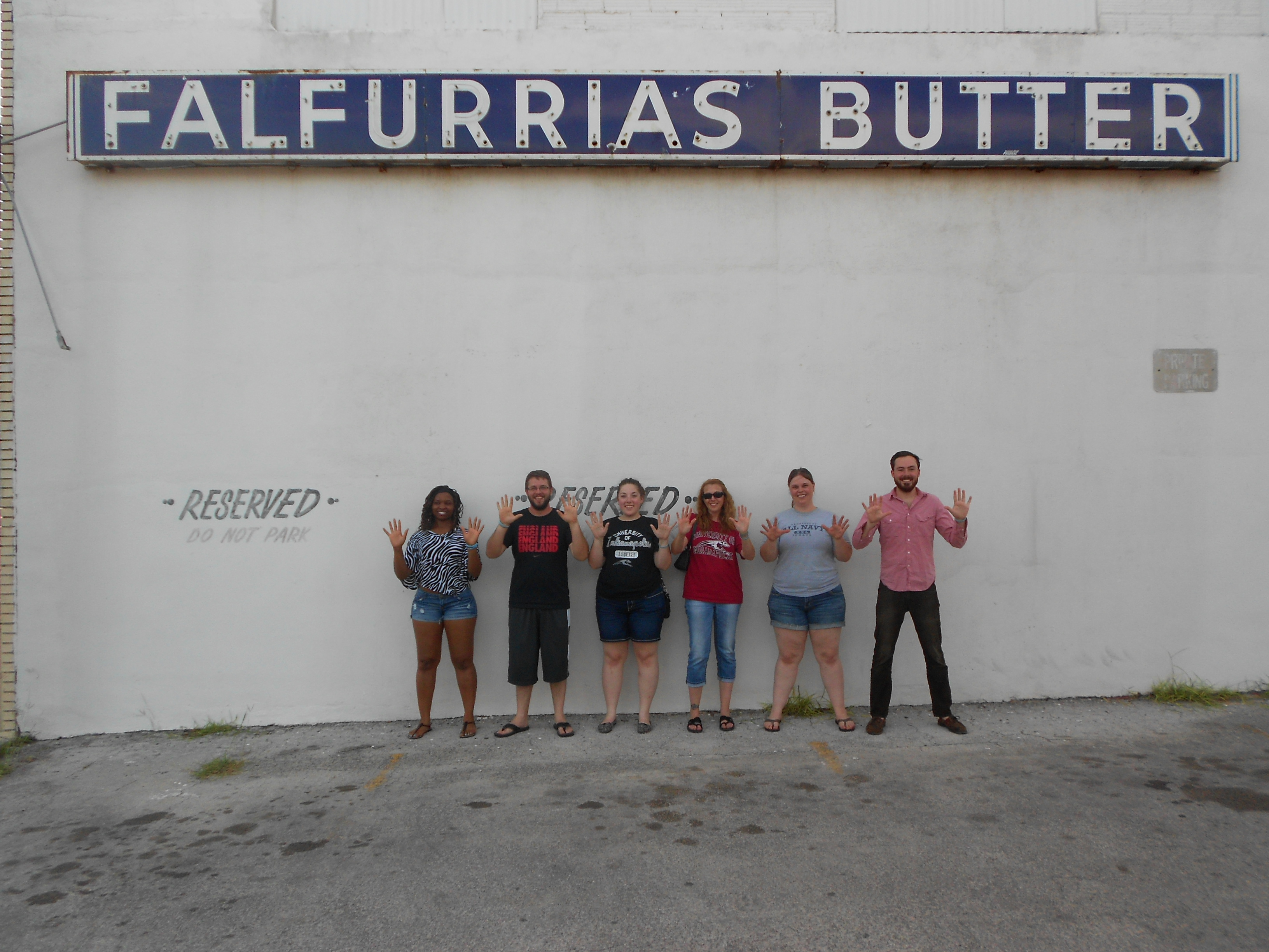 Group picture under a Falfurrias Butter sign with the members holding up ten fingers