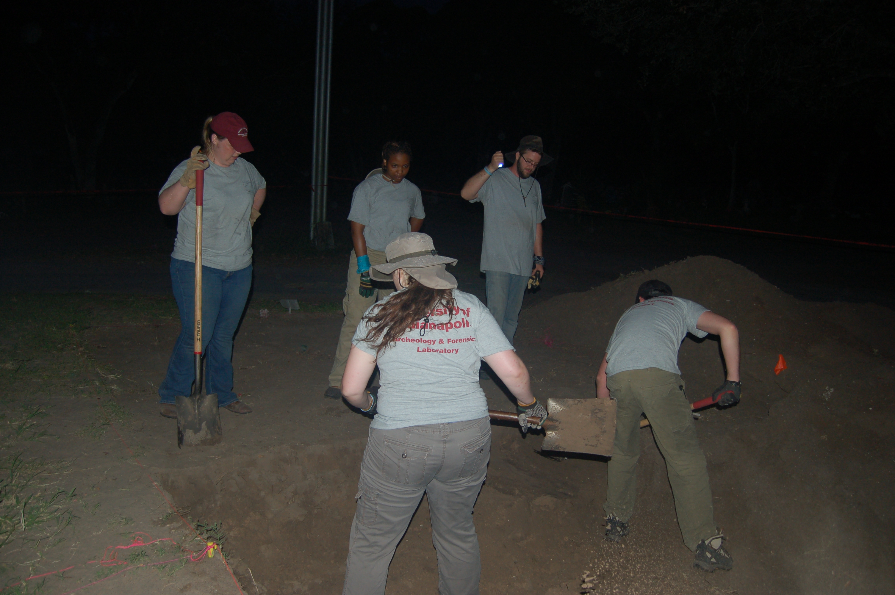 Team members digging with shovels in the dark
