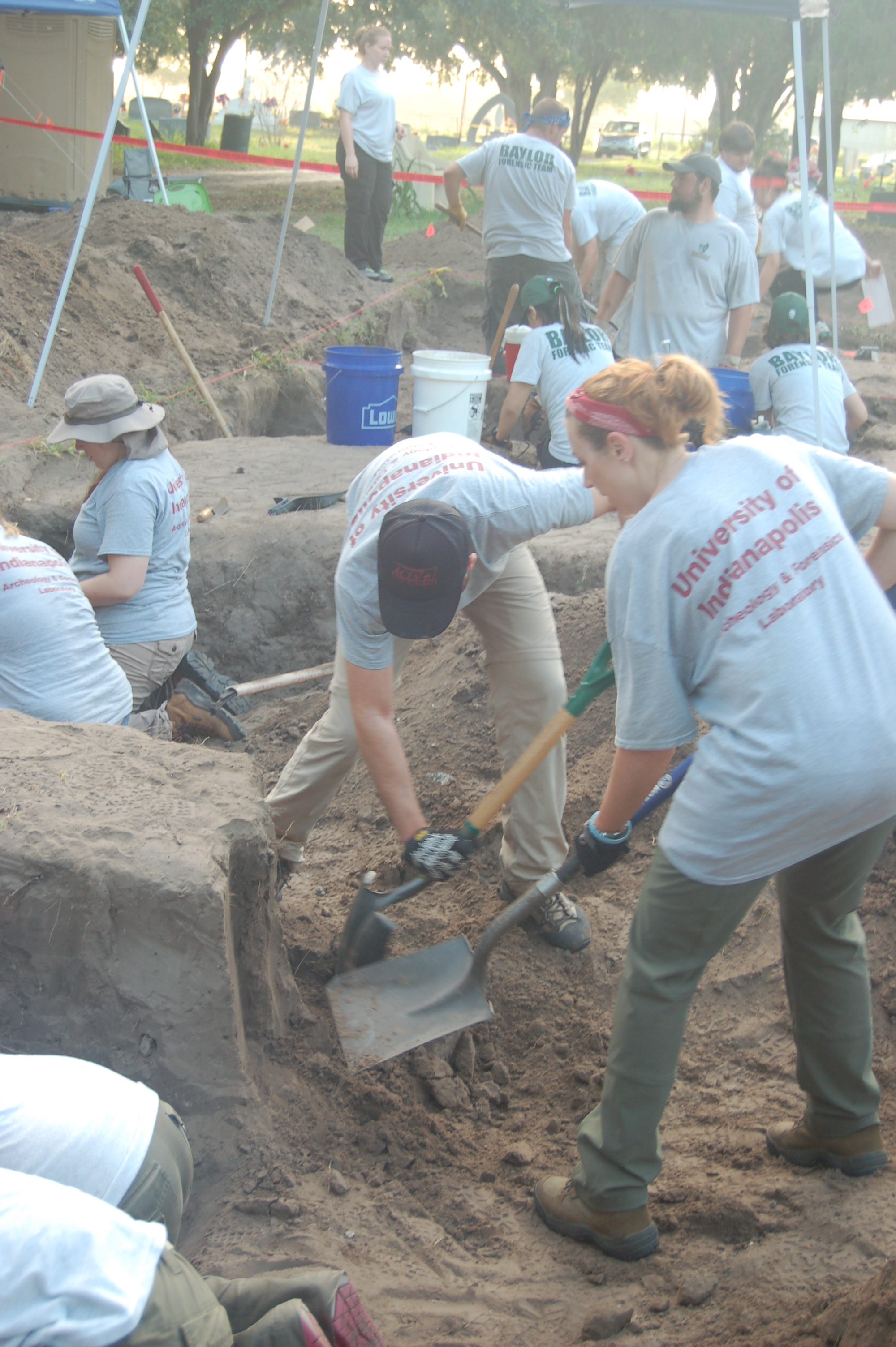 Beyond Borders team members using shovels on a wall inside a burial