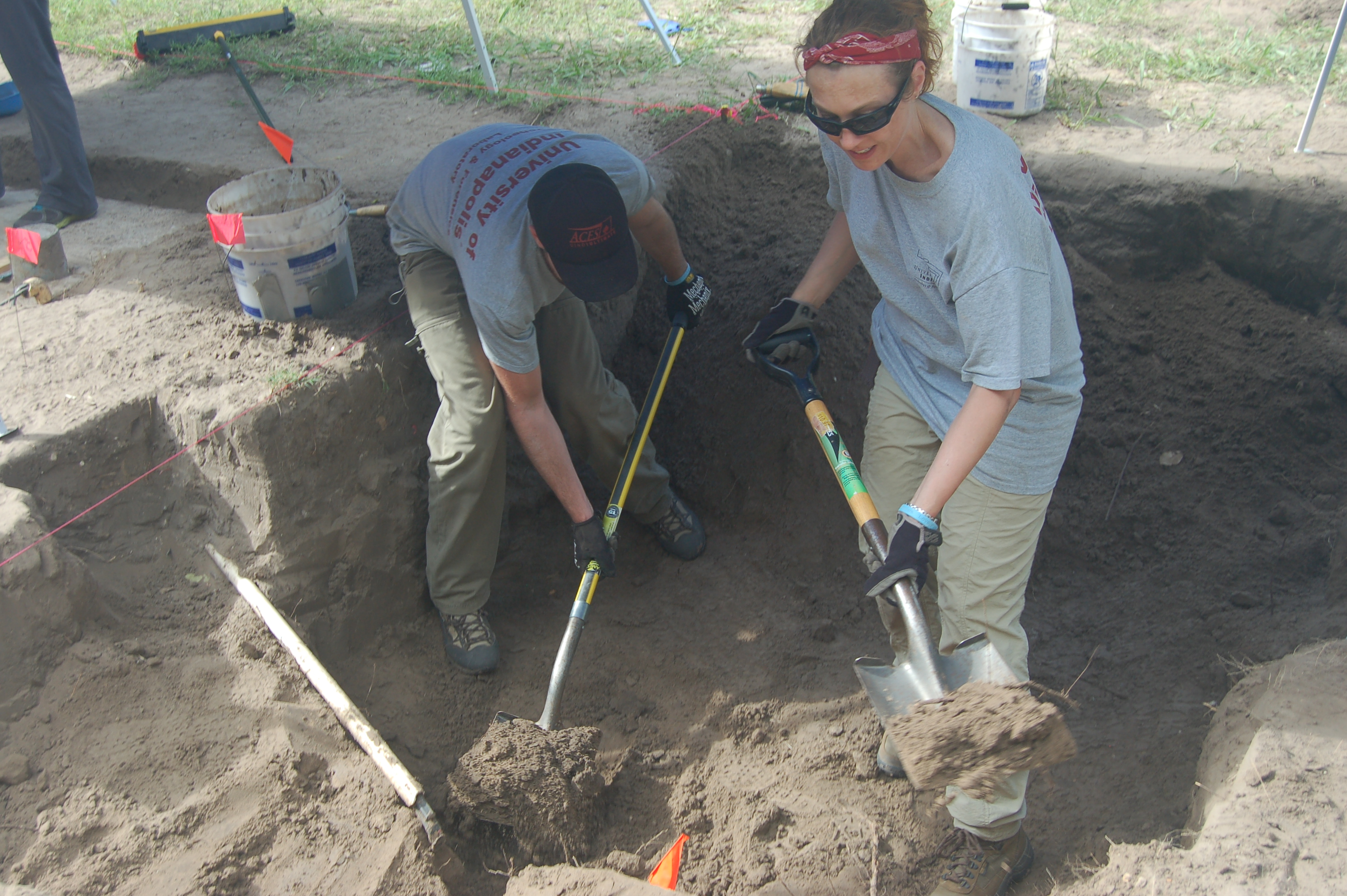 Team members digging with shovels within a burial