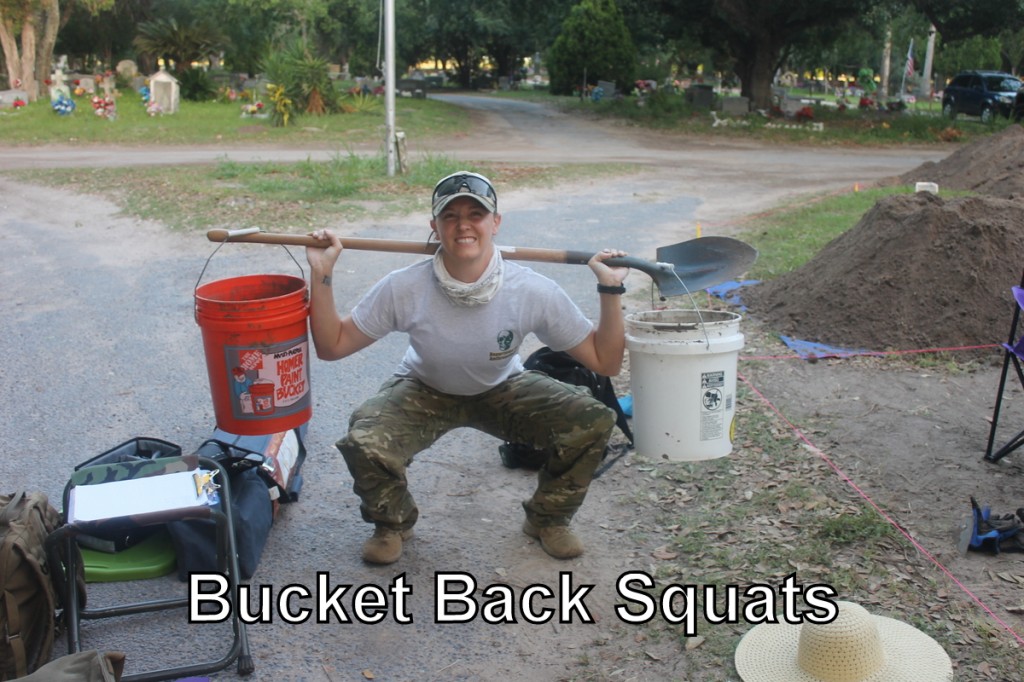 Team member squatting with a shovel over their shoulders and 5-gallon buckets on either side of the shovel