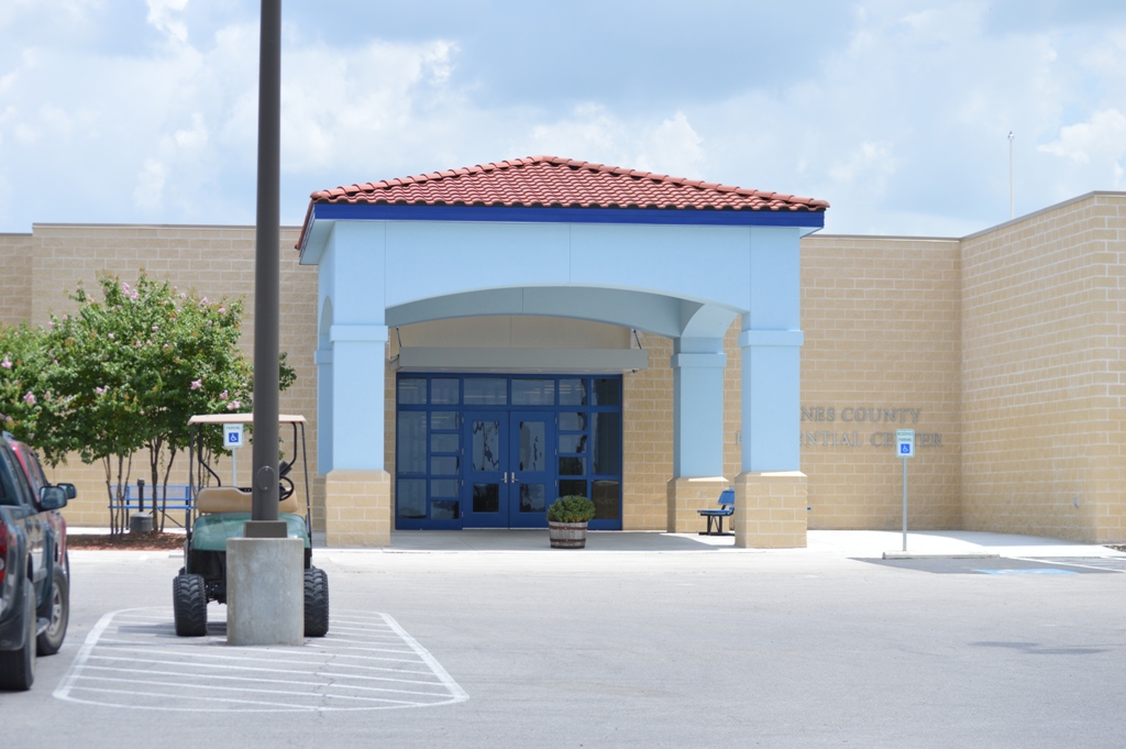 The front of Kernes County Residental Center with blue double doors, beige brick, and a light blue open way in front