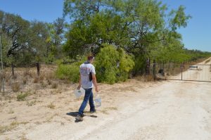 Rachel carrying gallons of water to refill a water station