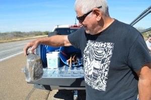 Eddie holding an empty migrant's water bottle, painted black. 