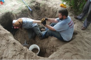 A man supporting a woman leaning into a trench