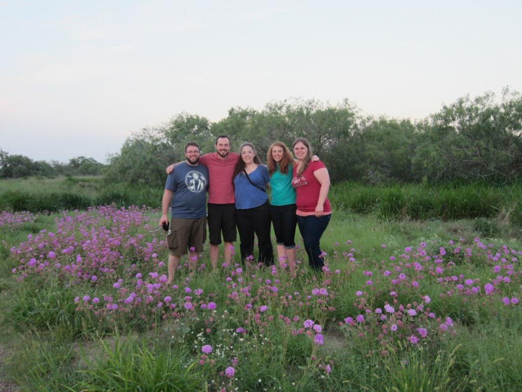 A group picture in a field of greenery and purple flowers