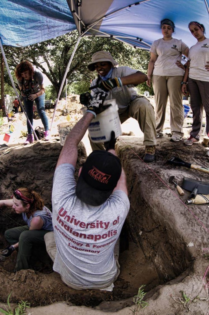 Beyond borders member passing a bucket from inside the burial to other team members on the ground level