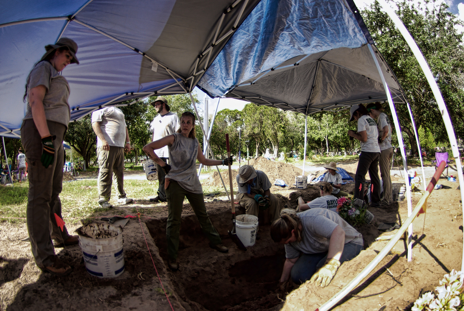 Team members working in a burial under a shade tent