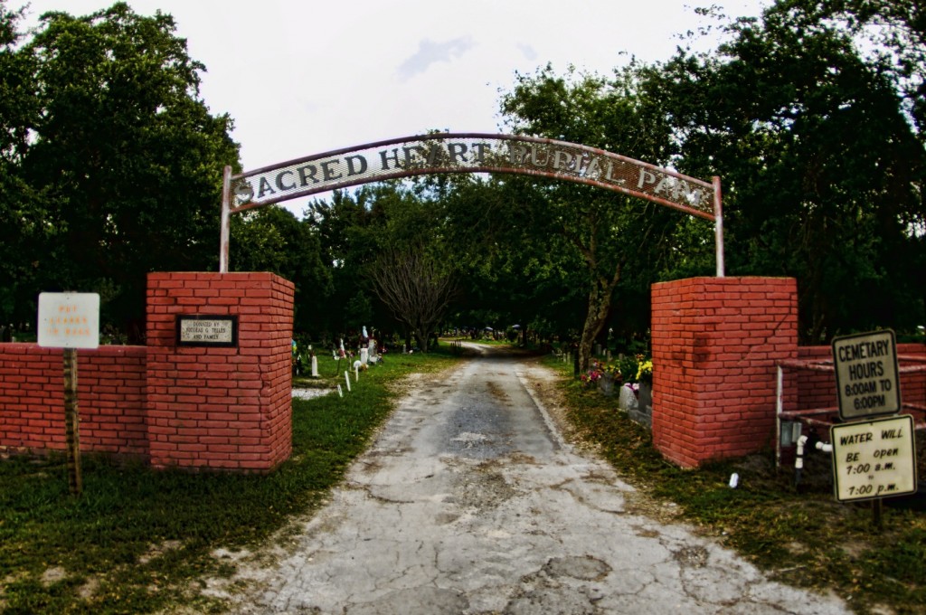 Sacred Heart entrance sign (white iron in red brick walls on either side of a road entering the area)