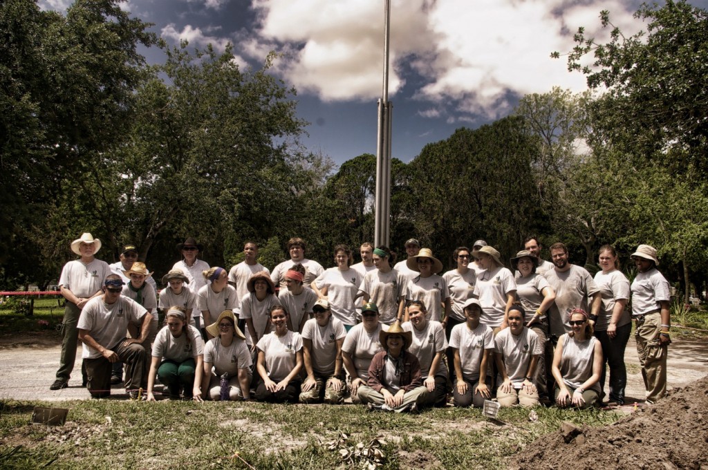 All members sitting and standing in rows for a full group picture, all in matching shirts and an array of hats and headbands