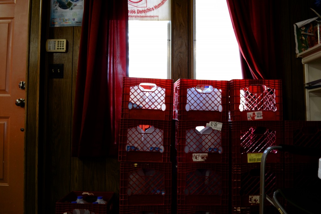 Stacks of milk crates filled with jugs of water infront of a window in the South Texas Human Rights Center