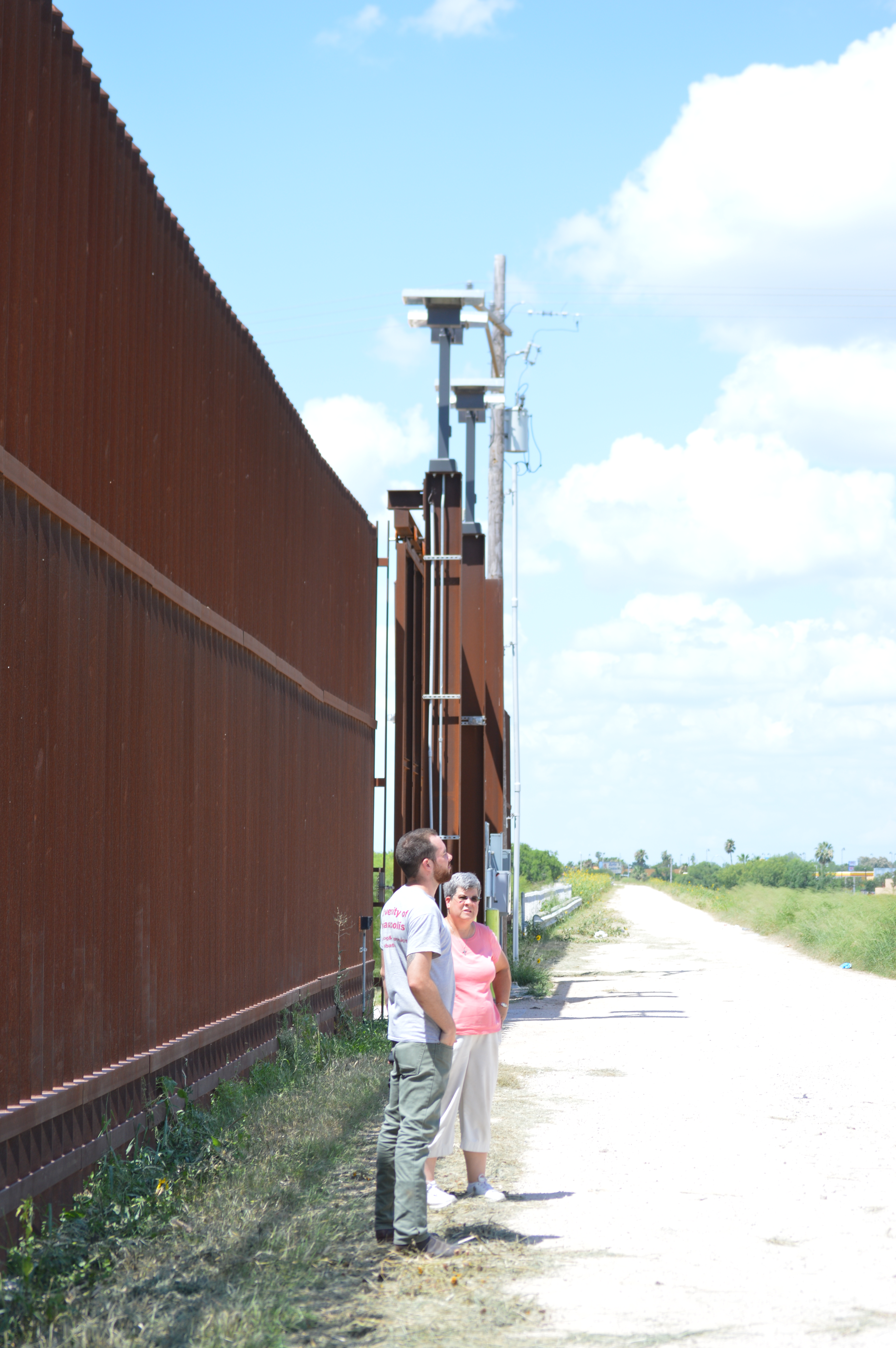 Sister Pam and Ryan standing infront of the border wall