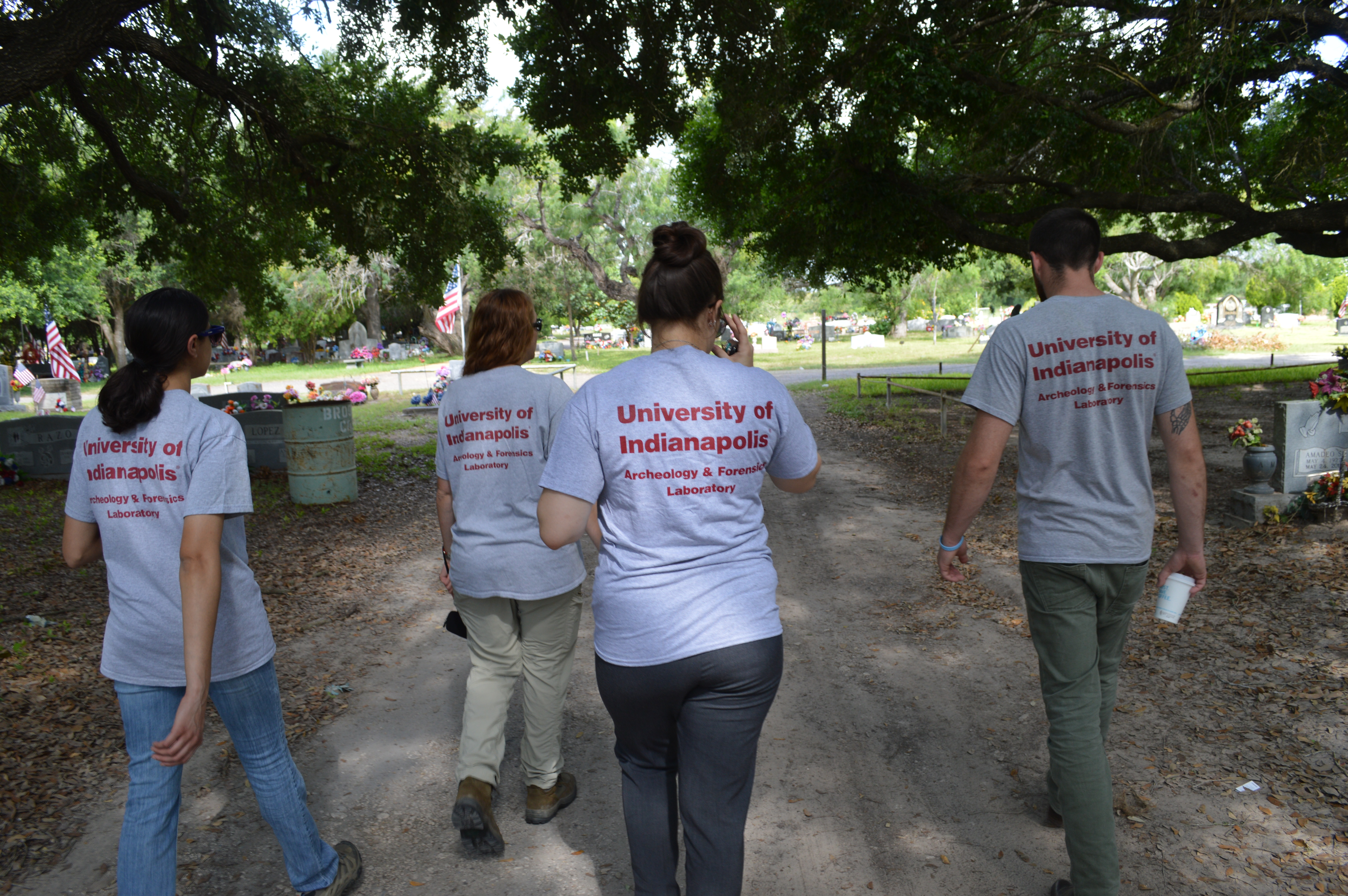 Beyond Borders team members walking through the cemetery with all UIndy Archaeology and Forensic Lab shirts on display