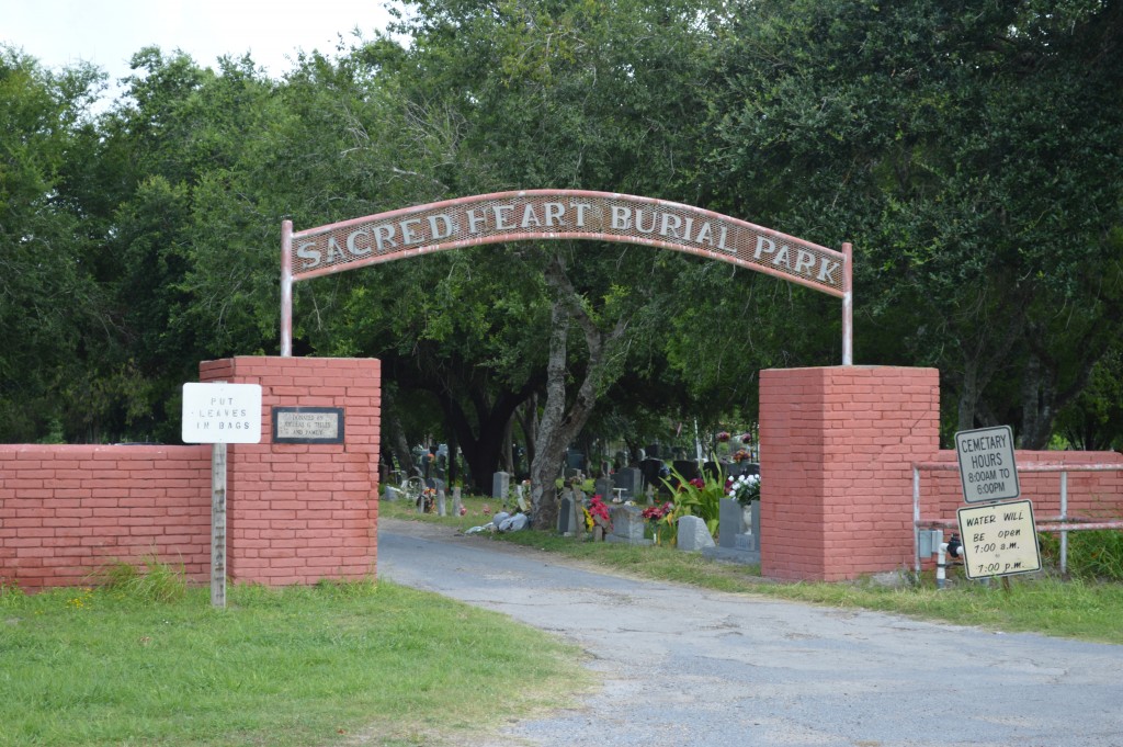 Sacred Heart Burial Park entrance sign over the road in red brick walls on each side
