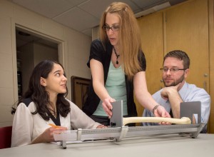Dr. Latham and graduate students Amanda Khan & Justin Maiers take measurements from a human bone with an osteometric board. 