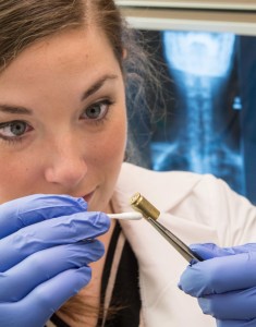 Graduate student Erica Christensen swabs a spent bullet casing for DNA analysis with a swab.