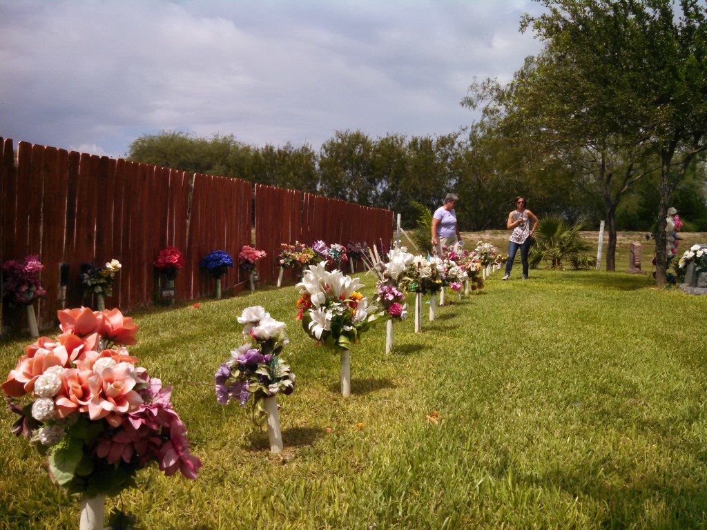 Dr. Spradley showing Sister Pam and Ryan a cemetery with the remains of unidentified individuals with white cross markers and flowers