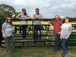 Two team members standing on a farm gate with three other members standing around them