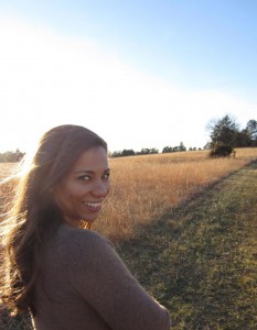 A woman smiling in front of a field.