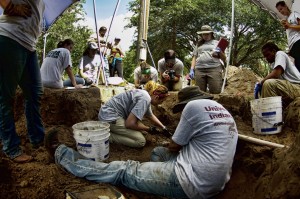 Two team members excavating in a trench as others look on from above