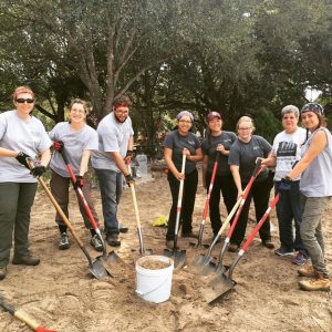 Team photo with shovels around a bucket of dirt.