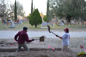 Two team members standing knee deep in a trench with shovels full of dirt.