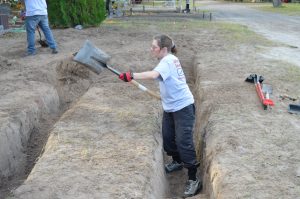 UIndy team member digging a trench.