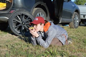 A team member kneeling on the ground with a compass.