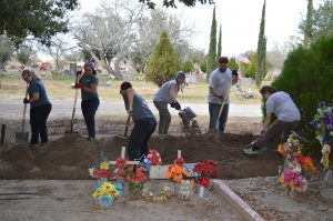 Team members filling in a trench with shovels