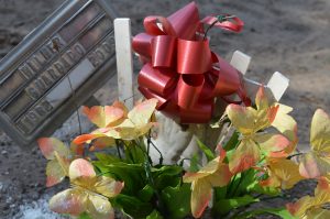 Metal grave marker with flowers.