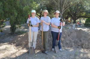 UIndy team members with shovels in front of a dirt pile