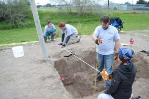 Four team members taking depth measurements of a burial