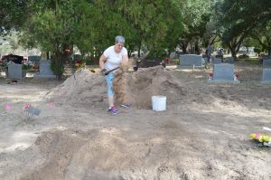 Sister Pam shoveling into a dirt pile.