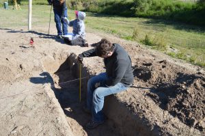 Team member measuring the depth of a trench.