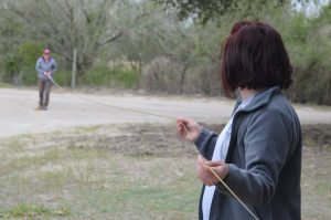 A team member holding the middle of a tape measure with another team member holding the end in the distance.