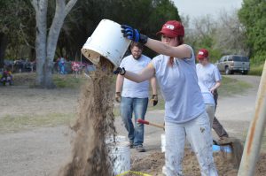 Team member dumping a bucket of dirt.