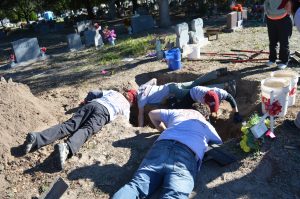 Team members laying down and reaching into a burial.