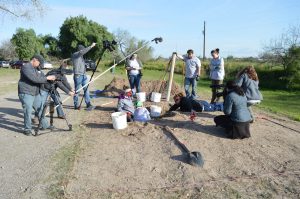 Media filming team members excavating a burial.