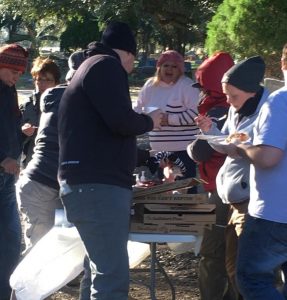 A group of people around pizza boxes.