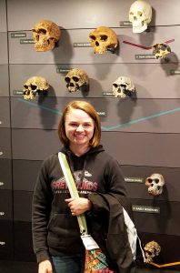 Team member Haley in front of skull exhibit