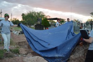 Team members removing a tarp from the trench.