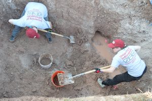 Team members using shovels in the trench.