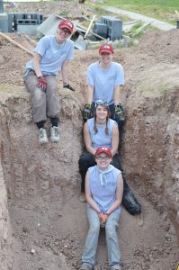 Group photo of team members sitting on the steps into the pit.