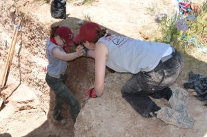 Team members helping each other out of the pit.