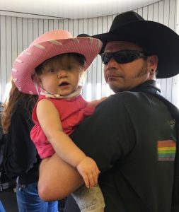 Man holding a toddler in cowboy hats.